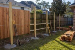 Wooden fence installation in progress in an Atascocita backyard with posts and materials ready